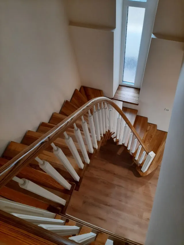 Medinių laiptų posūkis su baltais statramsčiais